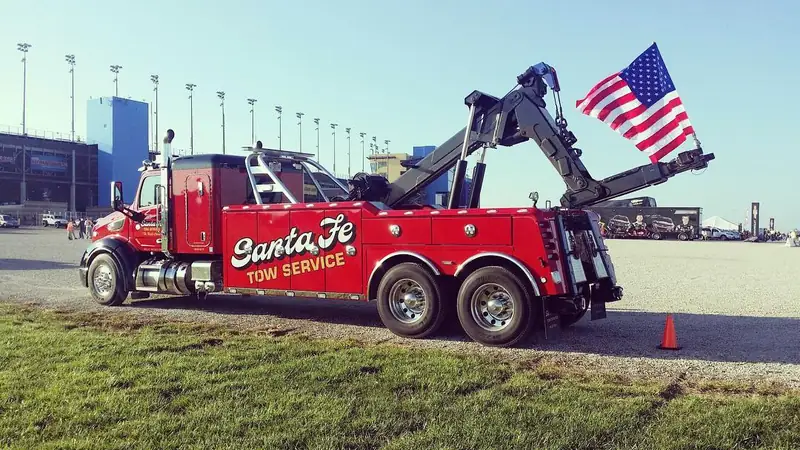 Santa Fe Tow Service professional driver standing in front of lowboy rig at golden hour